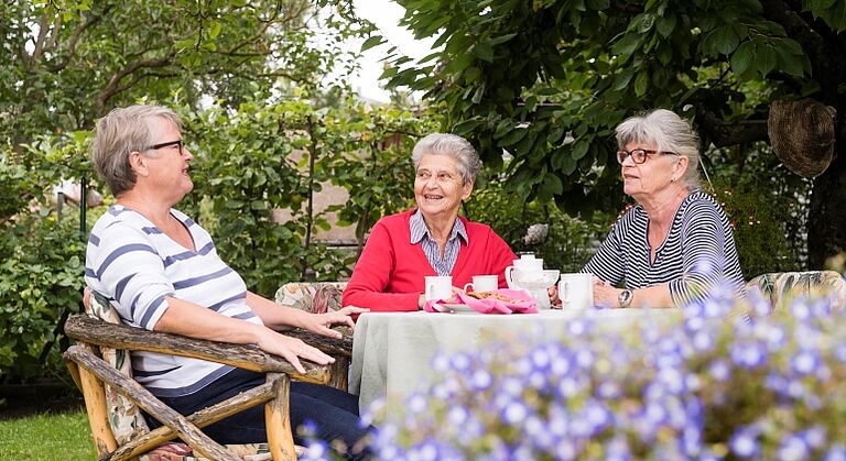 Drei Frauen beim Kaffeetrinken im Garten, organisiert durch das Seniorennetzwerk Nürnberg