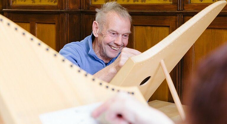 Mann mit Behinderung spielt eine Veeh-Harfe in der Seniorentagesstätte für Menschen mit Behinderung in Obernzenn