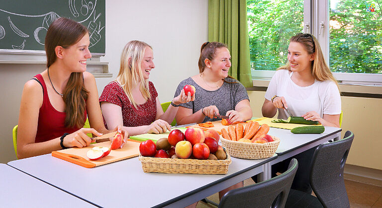 Vier Schülerinnen schneiden Obst udn Gemüse in der Schule für Hauswirtschaft Neuendettelsau, Ansbach, Bayern.