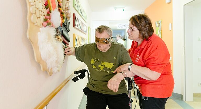 Bewohner mit Pflegefachkraft im Seniorenhof Pleinfeld beim Tasten von verschiedenen Materialien mit verbundenen Augen - dies dient zur Aktivierung der Sinne