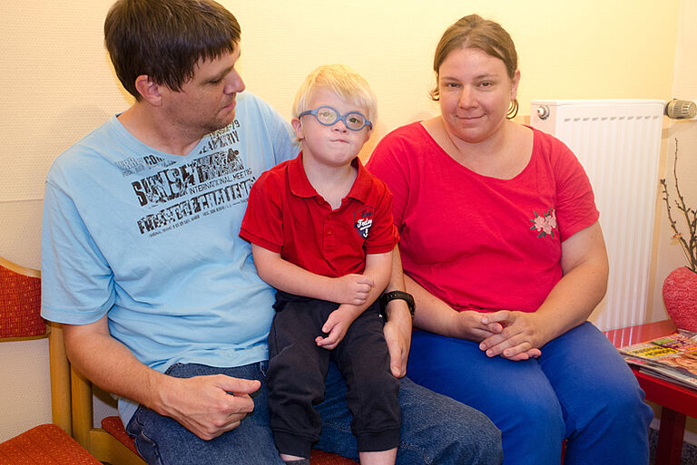 Ein Junge mit Down-Syndrom und seine Eltern.