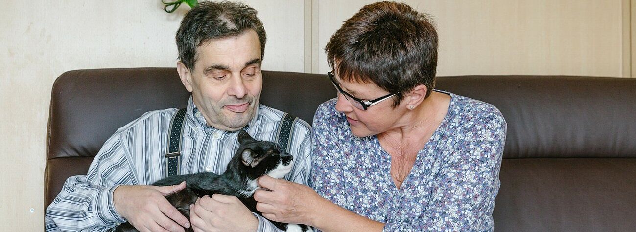 Ein Bewohner und eine Betreuerin streicheln eine Katze im Wohnheim für Menschen mit Behinderung in Obernzenn im Landkreis Neustad a.d. Aisch-Bad Windsheim