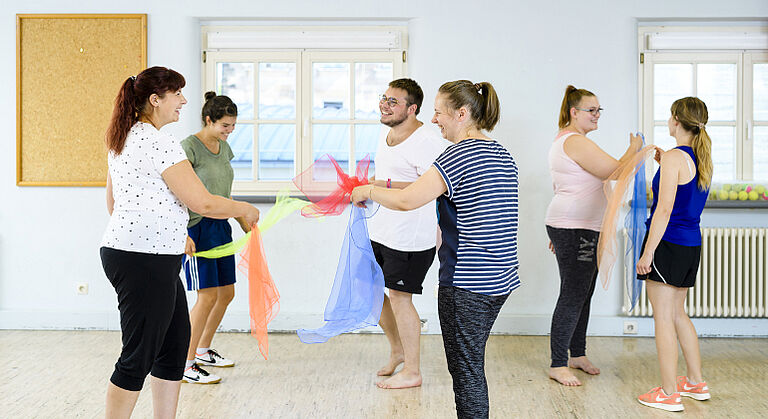 Schüler der Fachakademie für Sozialpädagogik in Fürth machen Bewegungsübungen mit Tüchern.