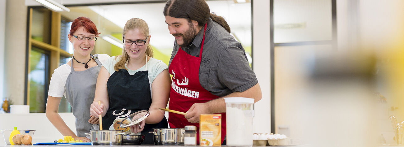 Auszubildende erlenen, wie sie Menschen mit Behinderung Hilfestellung beim Kochen geben.