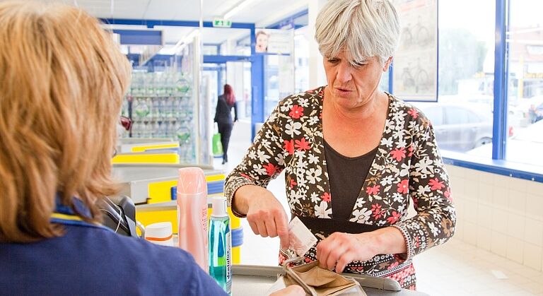 Frau beim Bezahlen an der Kasse bei einer Einkaufstour der Offenen Hilfen Rothenburg