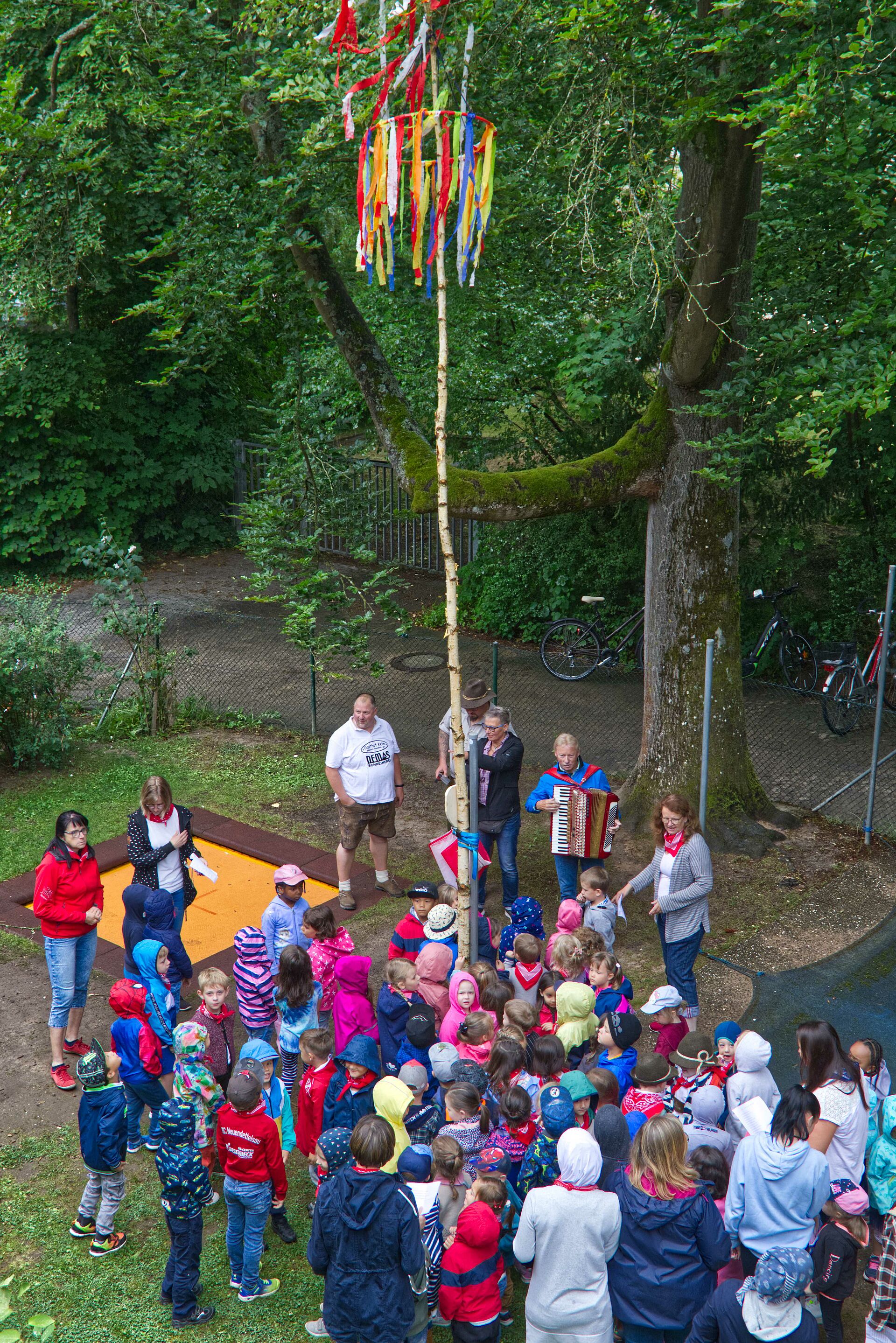 Kinder stehen um aufgestellten Kerwabaum